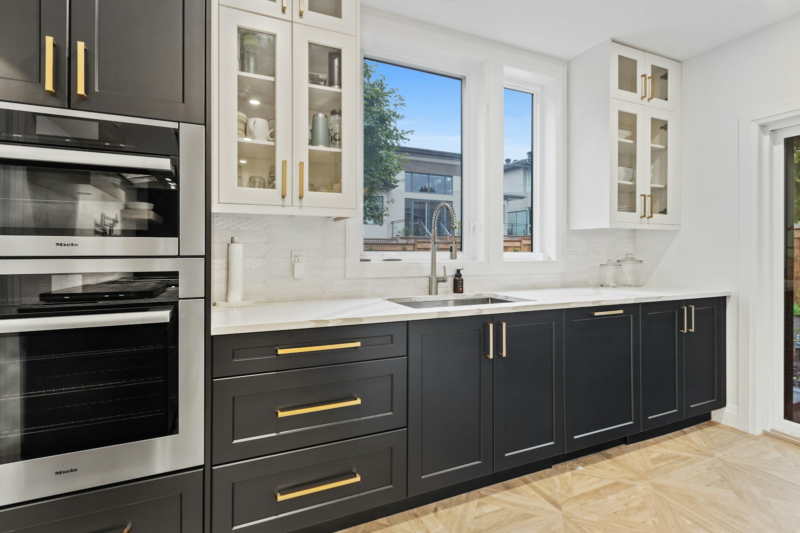 Custom black cabinetry with brass hardware and glass upper cabinets